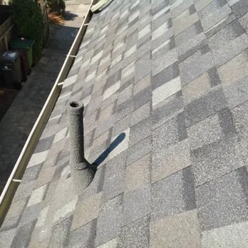 "A detailed view of a shingled roof with a vent pipe, showcasing expert roofing work by Roofing Logistics, Inc. in Oakland."
